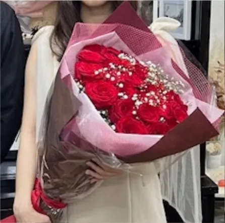 赤いバラ108本の花束を抱えた女性
