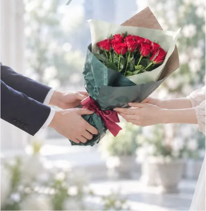 赤いバラの花束を手渡すふたりの手元