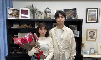 赤いバラの花束を持つお客様カップル