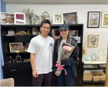 店舗で花束を預けるお客様とスタッフ